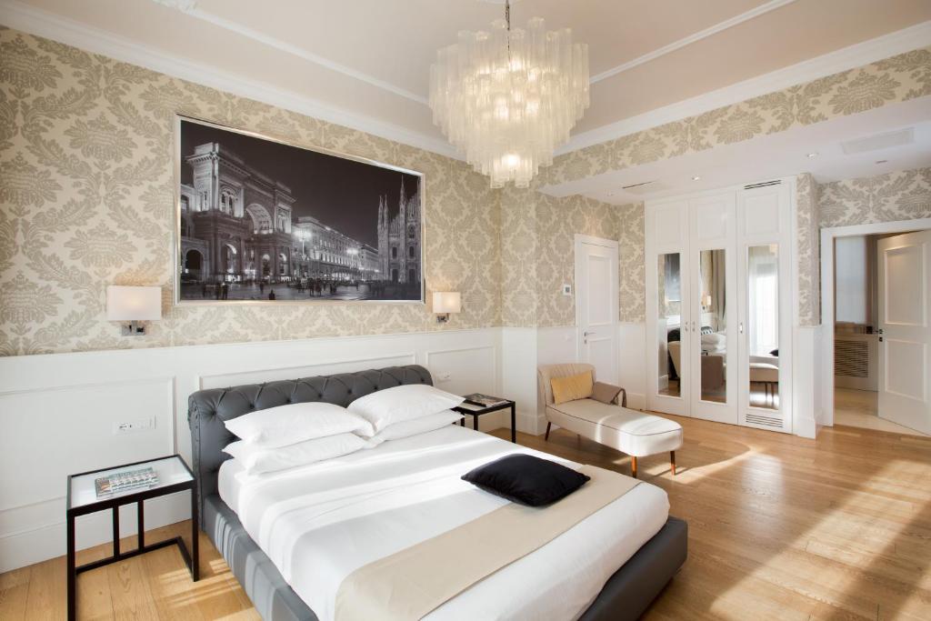 米兰米兰大教堂套房旅馆的一间卧室配有一张大床和一个吊灯。