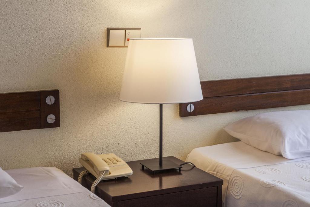 蓬塔德尔加达Hotel Sete Cidades的饭店房间桌子上的一盏灯,带电话