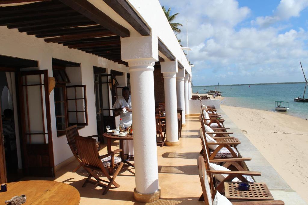 ShelaPeponi Hotel Lamu - Kenya的海滩上的餐厅,配有桌椅