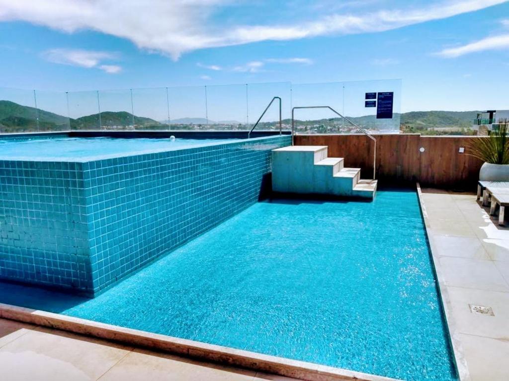 卡波布里奥Flat em Cabo Frio的大楼内一个蓝色瓷砖游泳池
