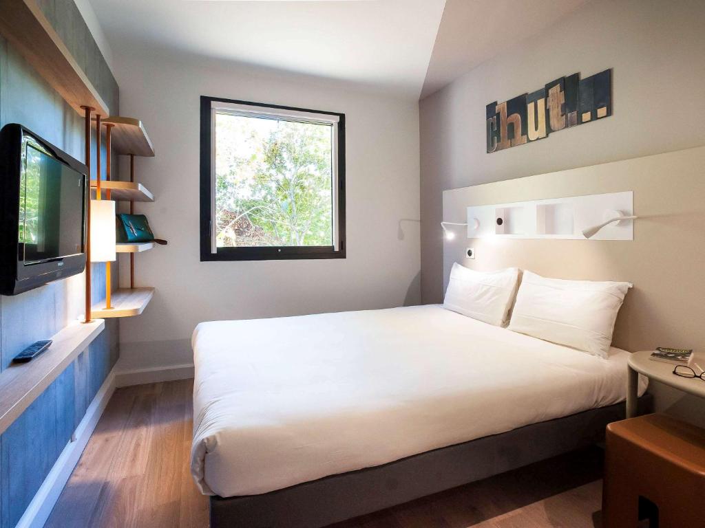 马恩河畔埃索姆ibis budget Château-Thierry的酒店客房设有一张大床和一台电视。
