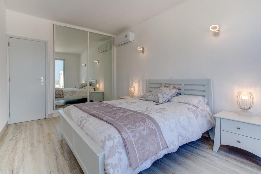 费拉古多Vila Gaivota 3G的白色卧室设有一张大床和镜子