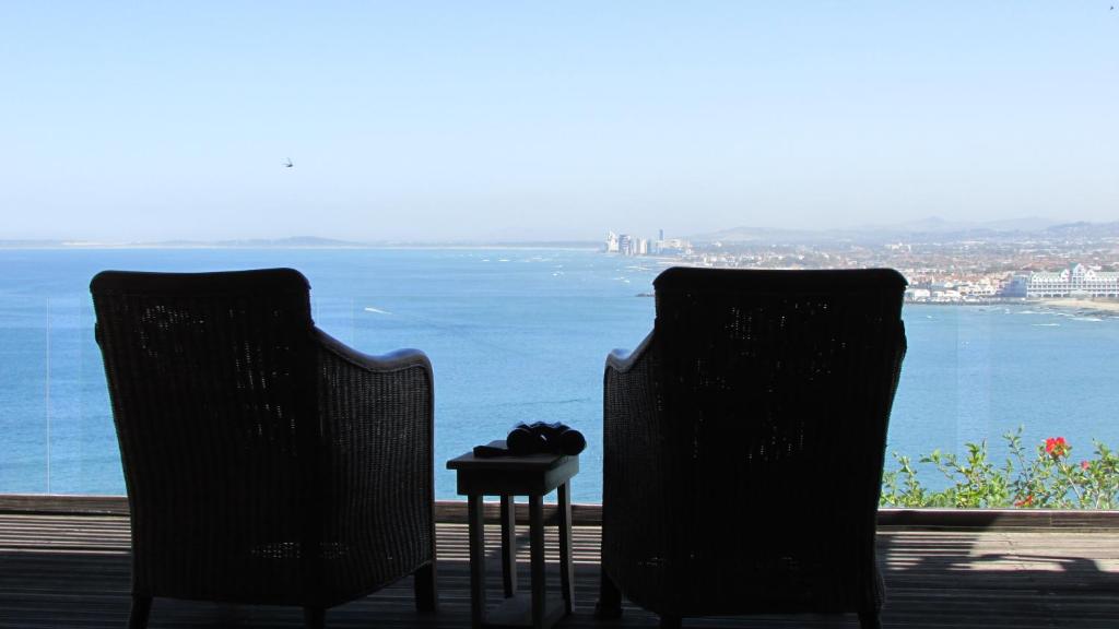 戈登湾Palm Tree Self-Catering Apartment的两把椅子和一张桌子,享有水景