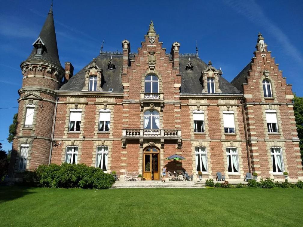 BaizieuxChâteau des marronniers的一座大型砖砌建筑,前面有一片绿色草坪