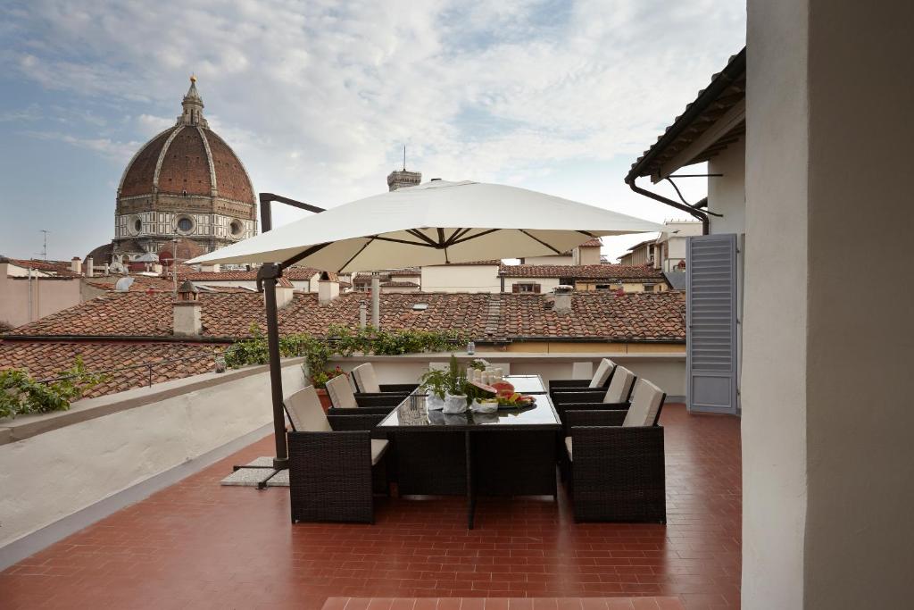 佛罗伦萨Penthouse with big terrace Duomo view的屋顶上带桌子和遮阳伞的天井