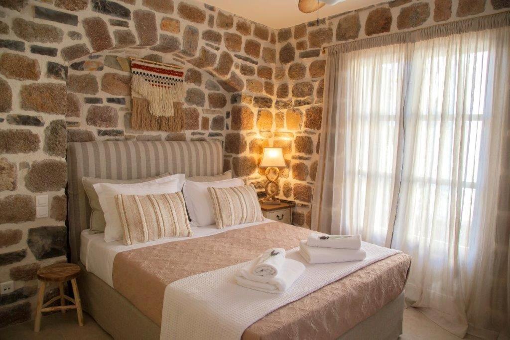 波罗斯Lithos Residence Poros的一间卧室设有一张带石墙的大床