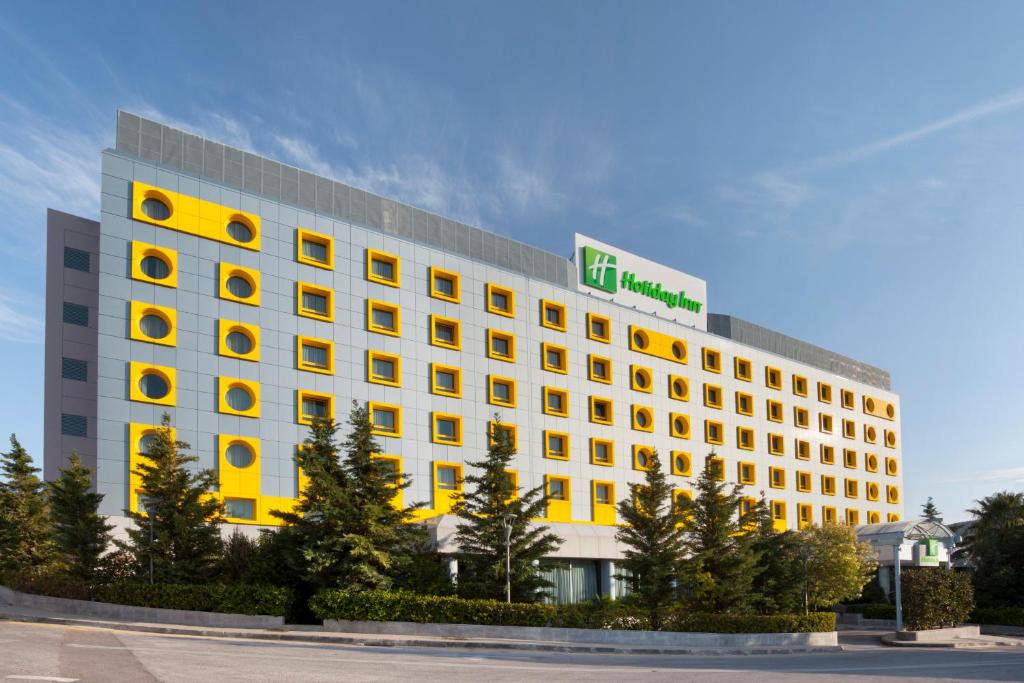 雅典Holiday Inn Athens Attica Av, Airport W., an IHG Hotel的上面有绿色标志的高大的白色建筑