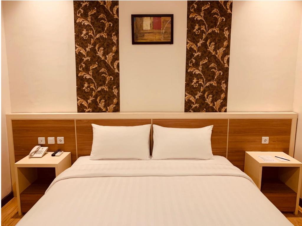班贾尔马辛Hotel 88 Banjarmasin By WH的一间卧室配有一张大床和两张桌子