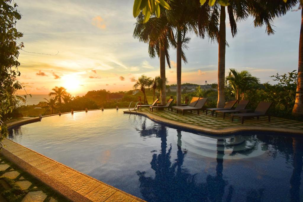 长滩岛索菲亚酒店的一个带椅子和棕榈树的游泳池,并可欣赏日落美景