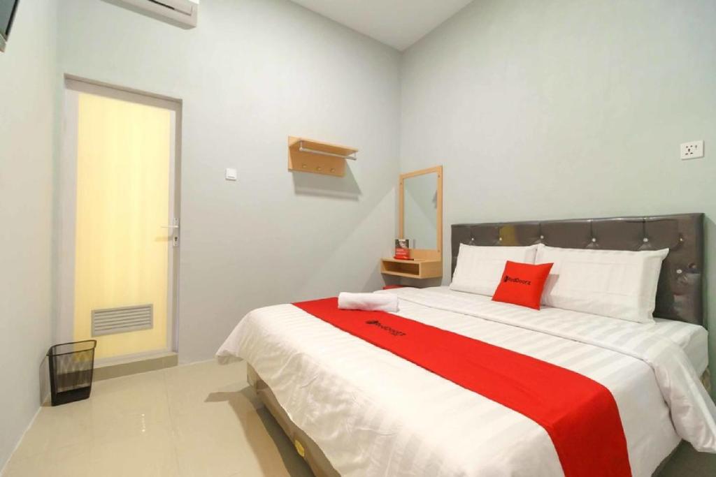 PulauberayanRedDoorz @ Helvetia Medan 2的一间卧室配有一张带红色毯子的大床