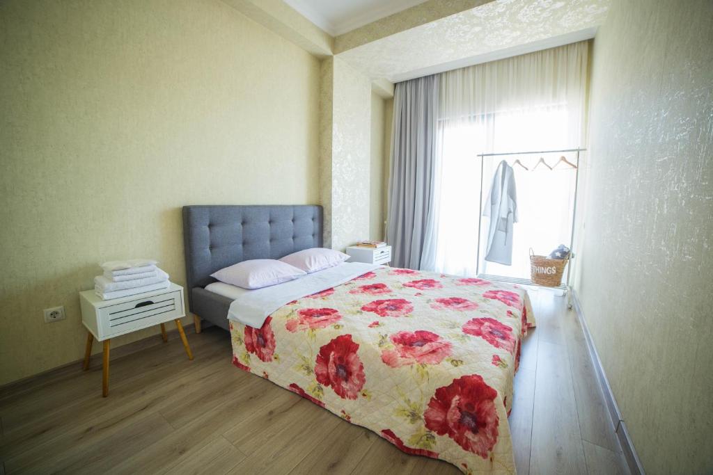 第比利斯Comfy Apartment的一间卧室配有一张带花卉床罩的床和窗户。
