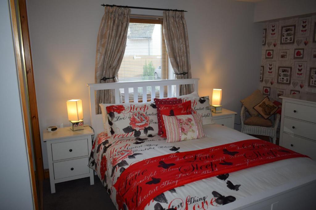 阿维莫尔Dunroamin Self-Catering Apartment的一间卧室配有一张带红色棉被和枕头的床