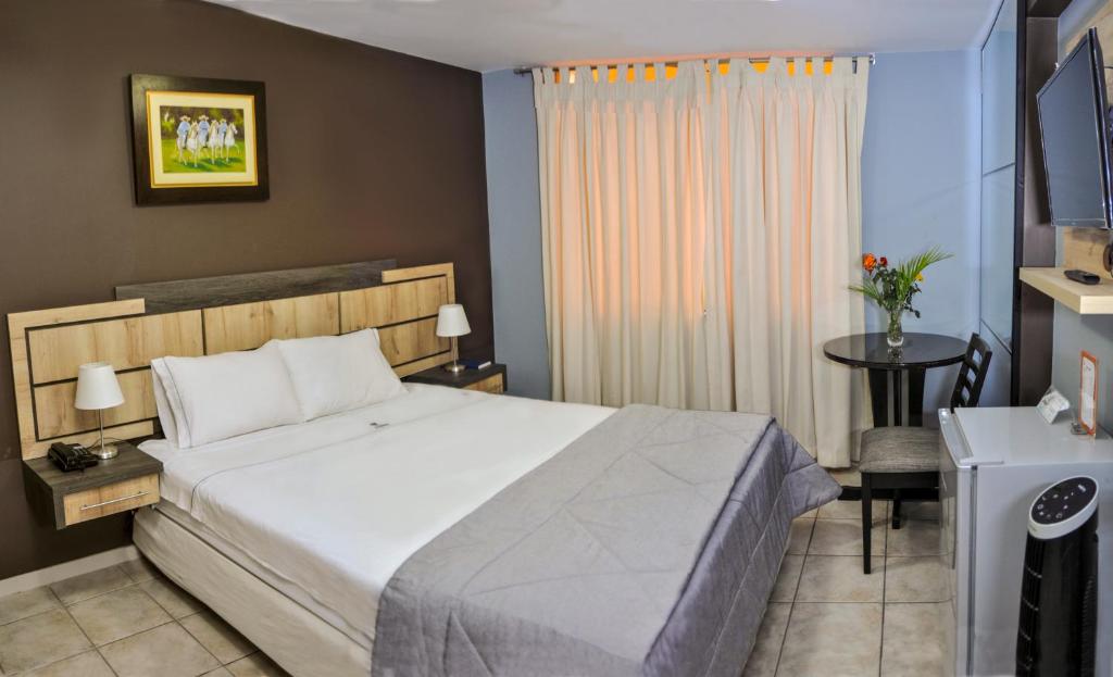 特鲁希略Hotel Chimu的一间卧室配有一张床、一张桌子和一个窗户。