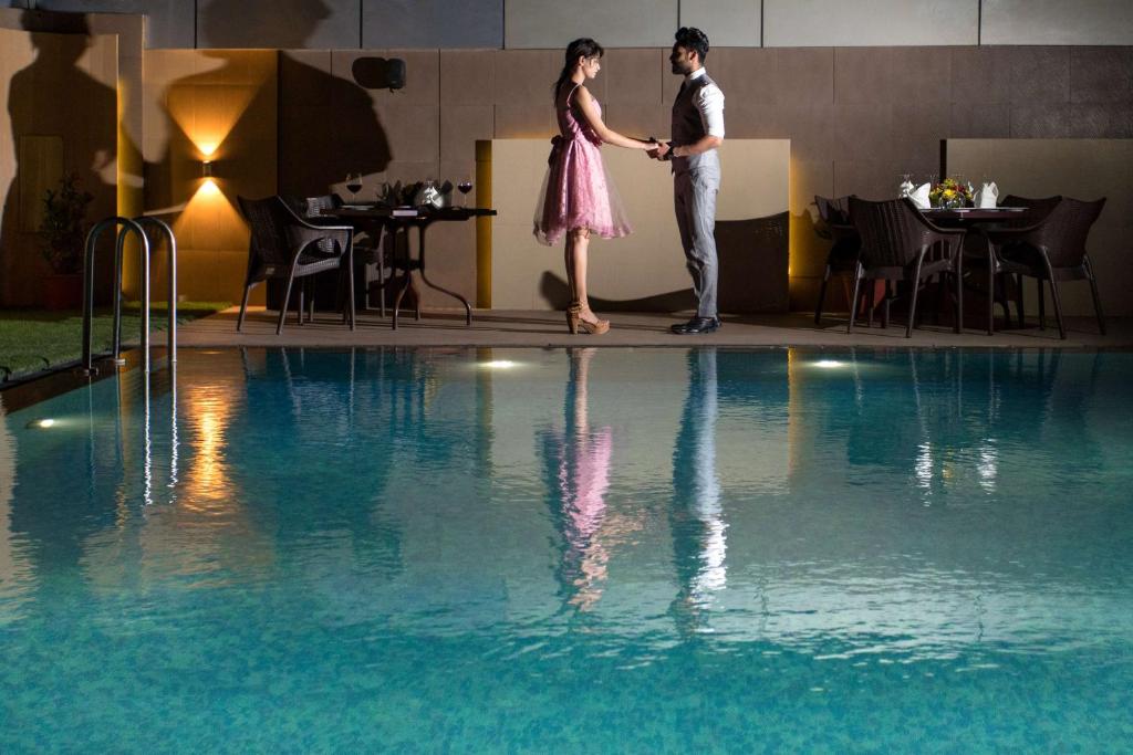 乌代浦乌代布尔丽筠酒店的站在游泳池旁的男女