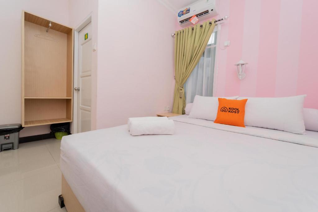 Klandasan KecilKoolKost Syariah near Taman Bekapai Balikpapan的卧室配有一张带橙色枕头的大型白色床。