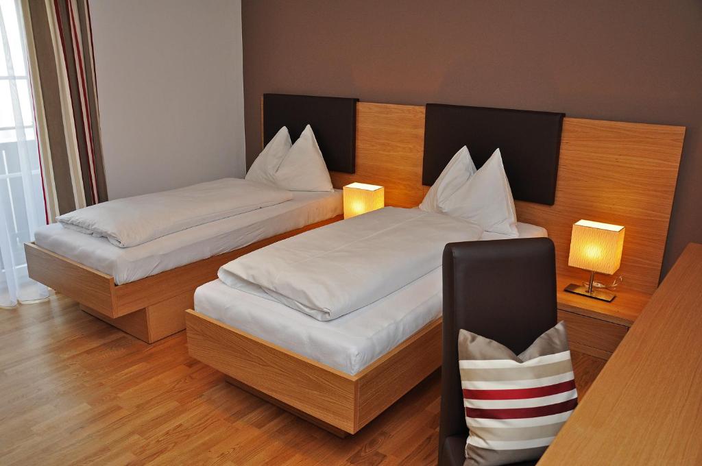 比绍夫斯霍芬格斯特霍夫蒂洛尔维特酒店的一间卧室设有两张床,墙上有两盏灯。
