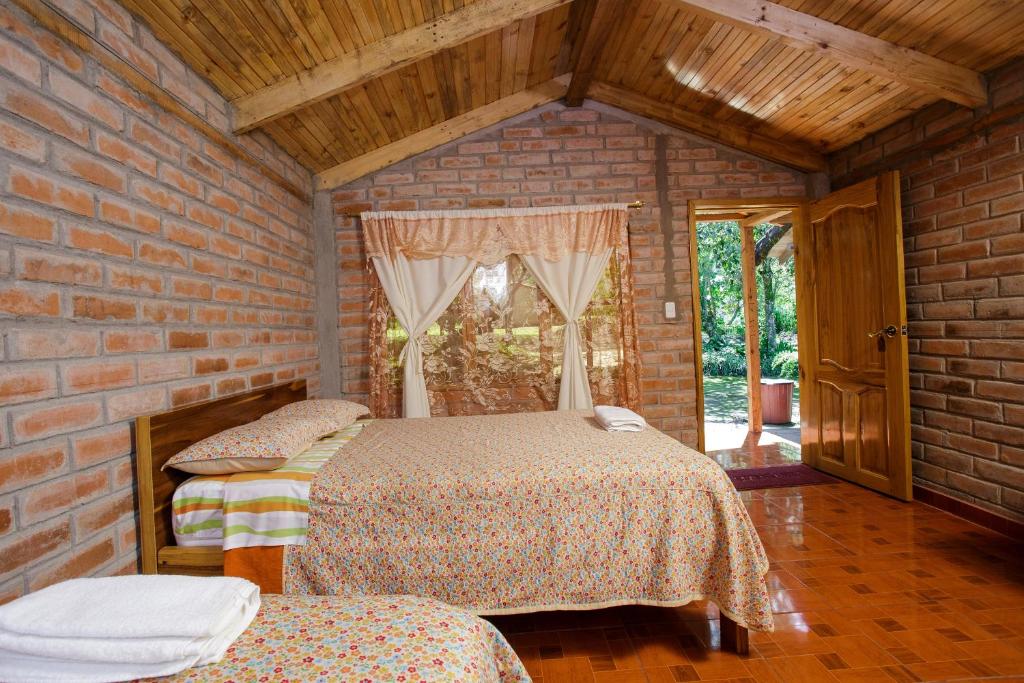 Vacas GalindoEstancia, CABAÑAS INTAG的砖墙内一间卧室,配有两张床
