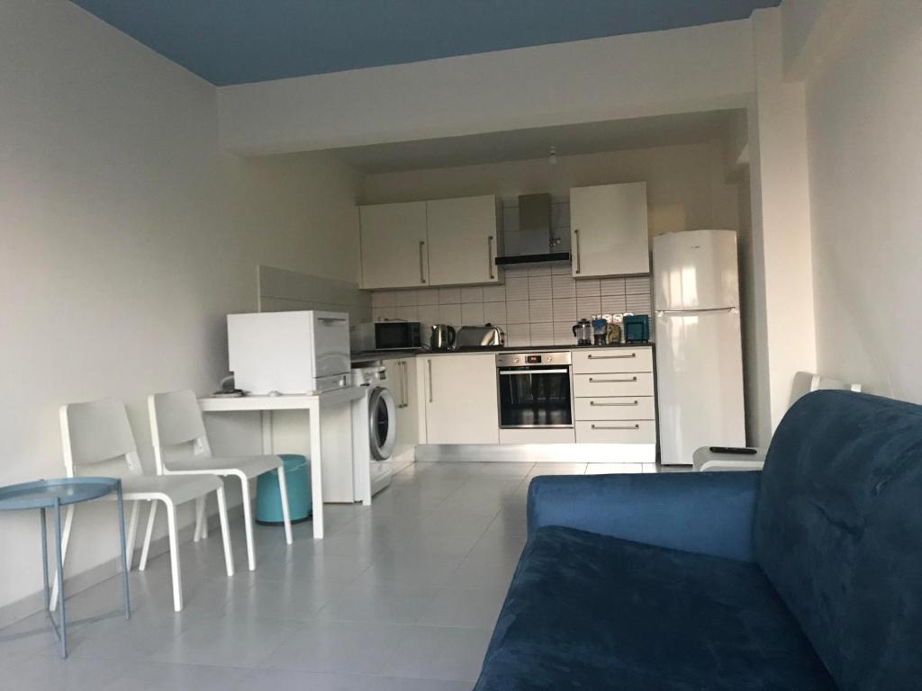 马佐托斯Mazotos 54m2 One Bedroom Flat, "Panoramic Village"的一间带蓝色沙发的客厅和一间厨房