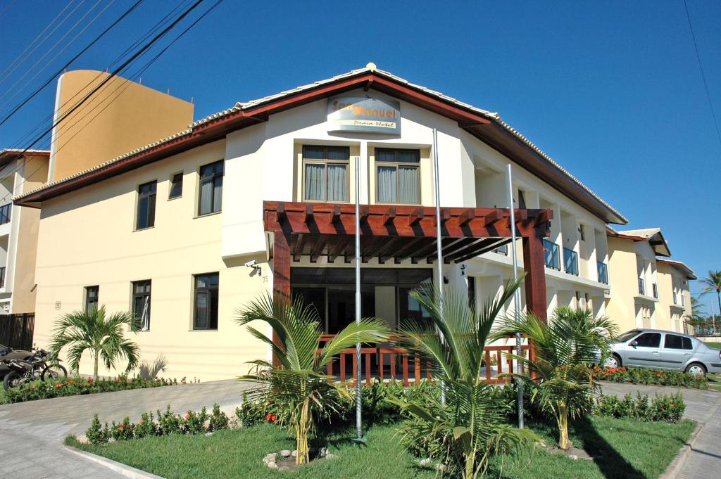 阿拉卡茹圣曼努埃尔普拉亚酒店的一座白色的大建筑,前面有棕榈树