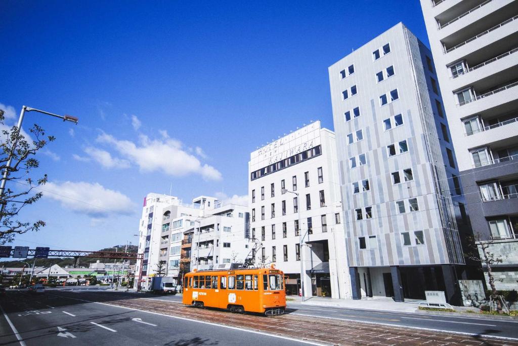 松山Hotel Kajiwara的停在城市街道上的橙色巴士,有建筑
