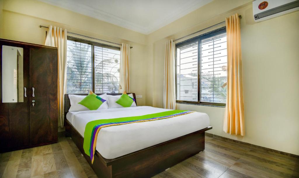 浦那Treebo Trend Yash Inn Kharadi的卧室配有带绿色枕头的大型白色床