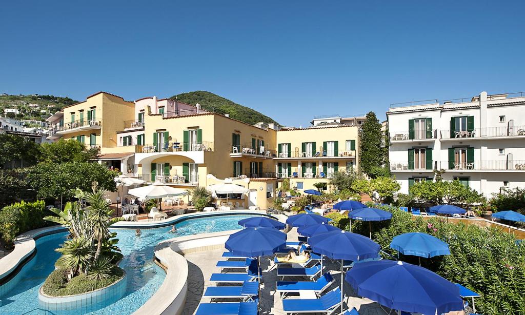 伊斯基亚皇家温泉酒店的一个带蓝色遮阳伞和椅子的游泳池的度假酒店