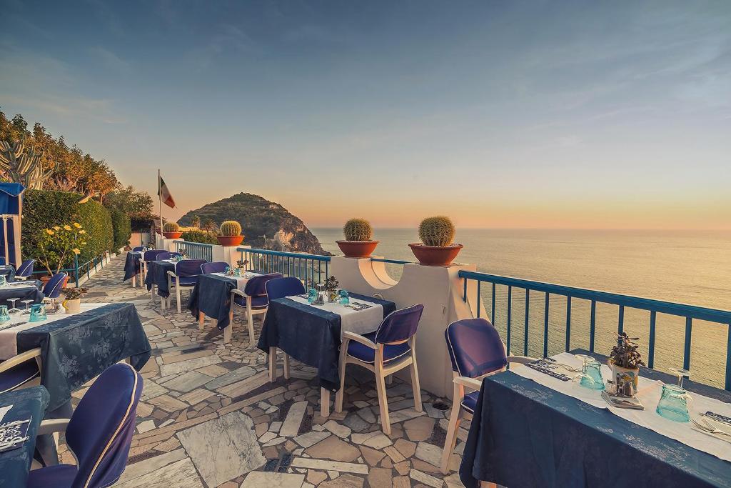 伊斯基亚Hotel Villa Maria的一间位于海边的餐厅,配有桌椅
