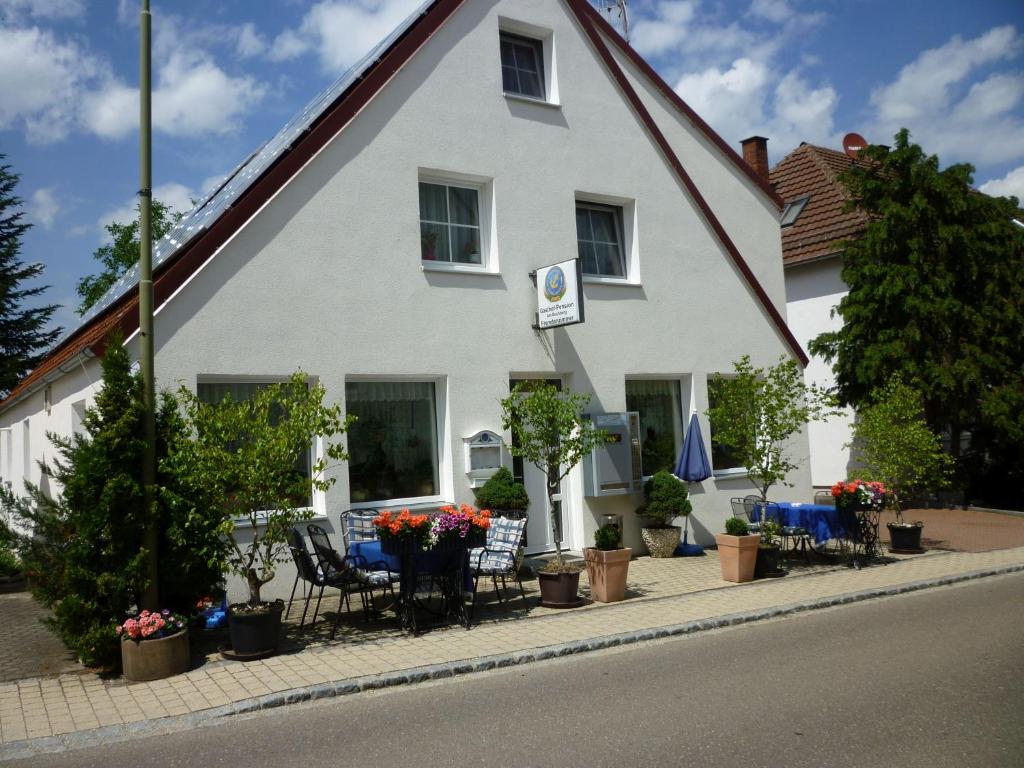 MönchsdeggingenGasthaus - Pension Am Buchberg的白色的房子,配有桌子、椅子和植物