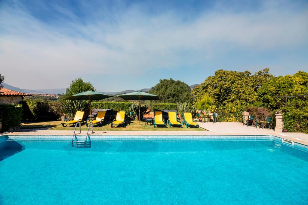 蓬德利马Quinta Da Aldeia的一个带椅子和遮阳伞的游泳池