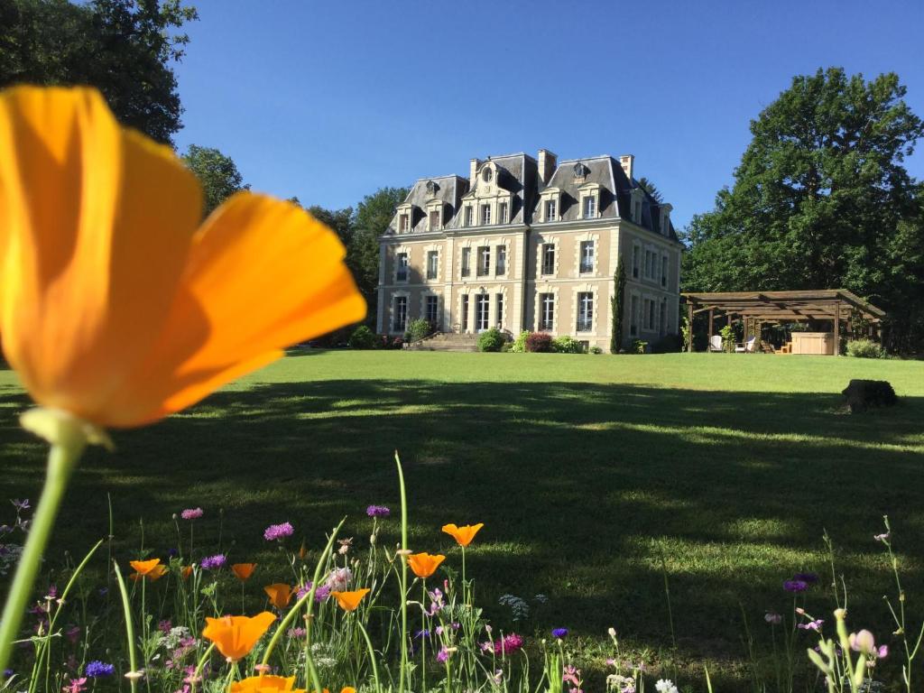 朗热Château des Essards avec piscine et jacuzzi的一个大房子前面的黄色花朵