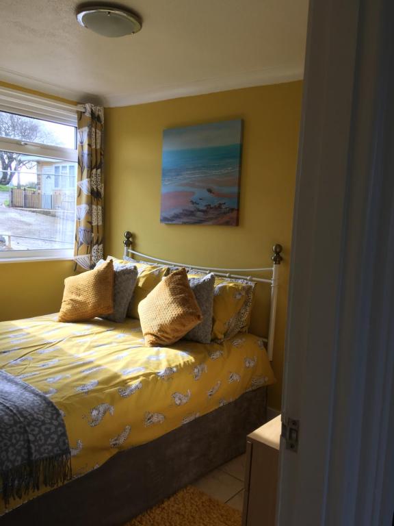 桑当8 Sandy Bottom Sandown Bay Holiday Park, reduced ferry, please contact us的一间卧室配有一张带黄色床单的床和一扇窗户。