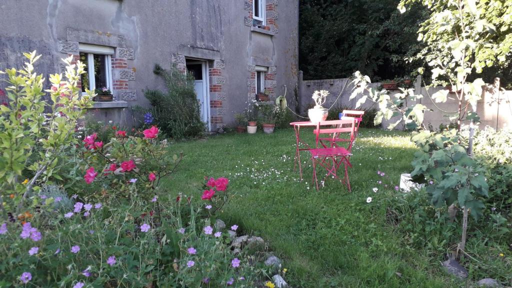 布列塔尼地区米尔Chambre d hôte chez Fany的花园设有两把椅子和一张桌子,种有鲜花