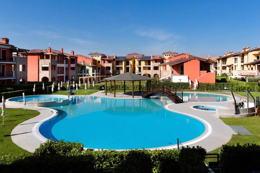 西尔米奥奈Appartamento Corina的一座大型游泳池,位于一座拥有建筑物的公园内