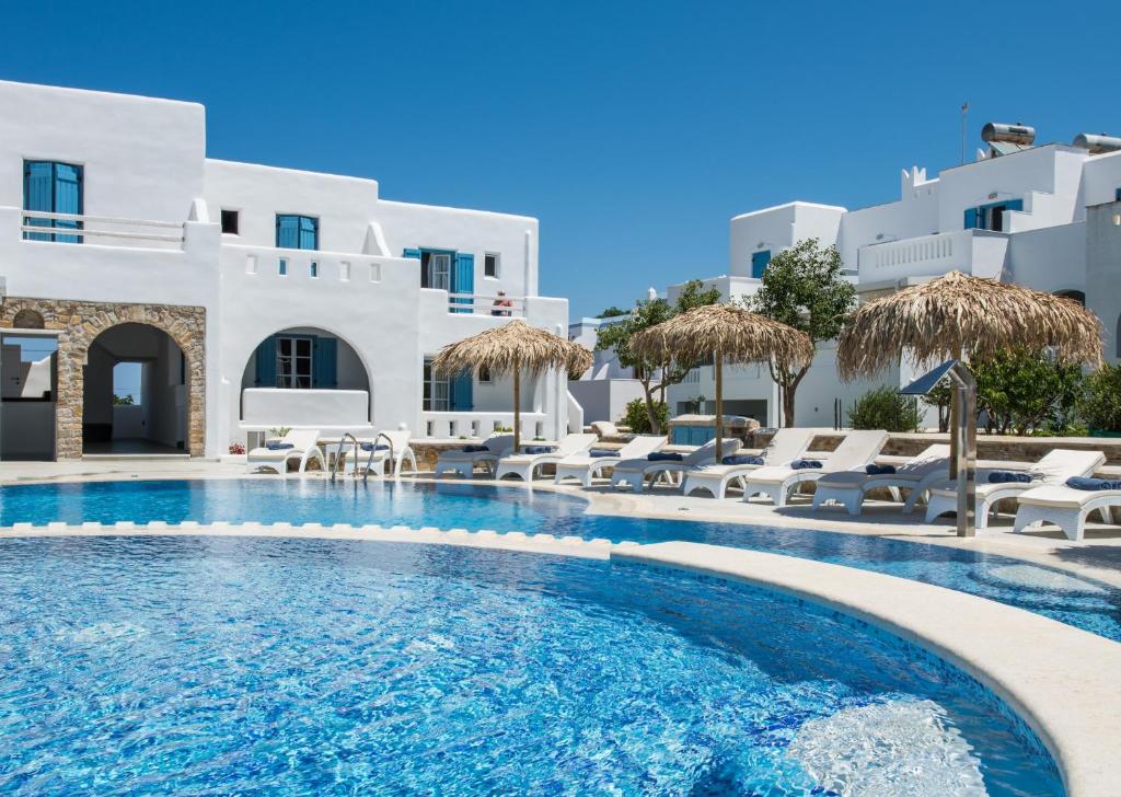 圣安娜纳克索斯Cycladic Islands Hotel & Spa的酒店前方的游泳池配有椅子和遮阳伞