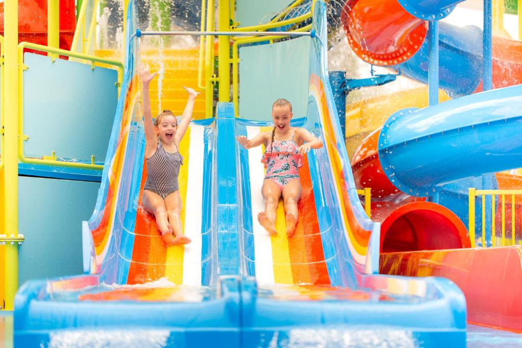 黄金海岸BIG4 Gold Coast Holiday Park的两个孩子在水上公园的水滑梯玩耍