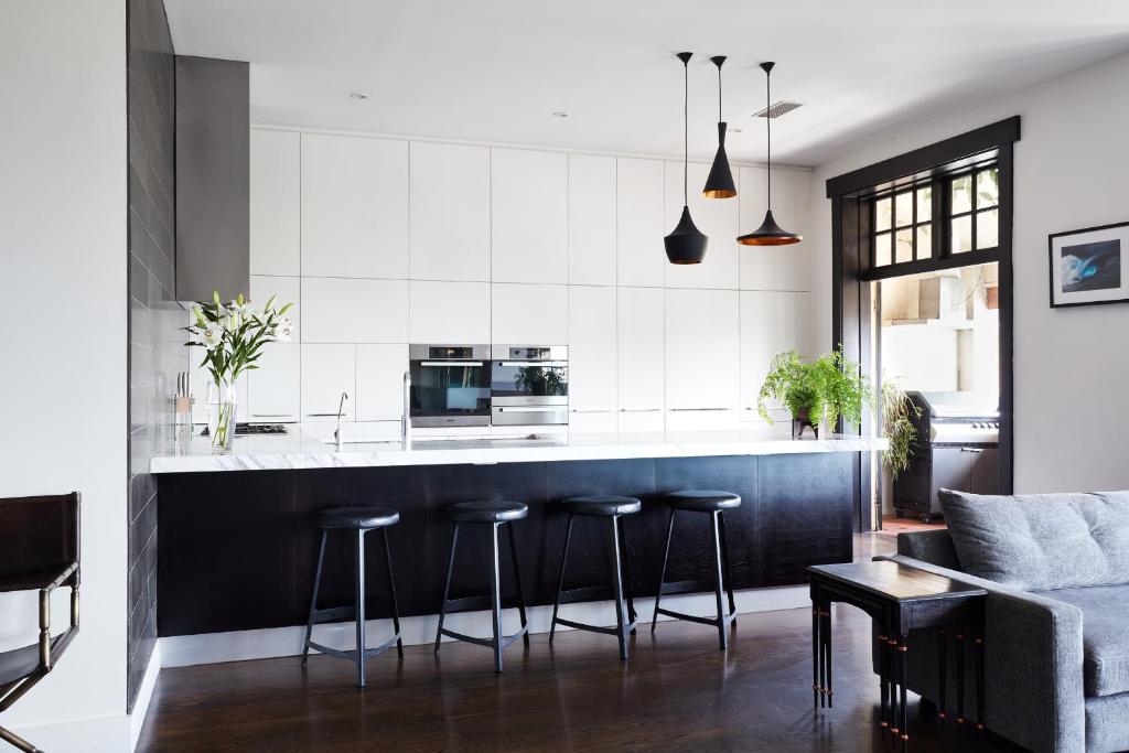 墨尔本St Kilda Beachfront Penthouse的厨房配有黑白台面和凳子