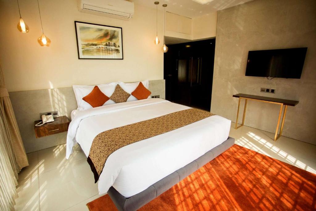 达卡Jatra Flagship Dhaka Lake View的一间卧室配有一张大床和一台平面电视