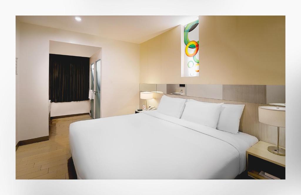 马尼拉Go Hotels Ortigas Center的一张大白色的床,位于酒店客房内