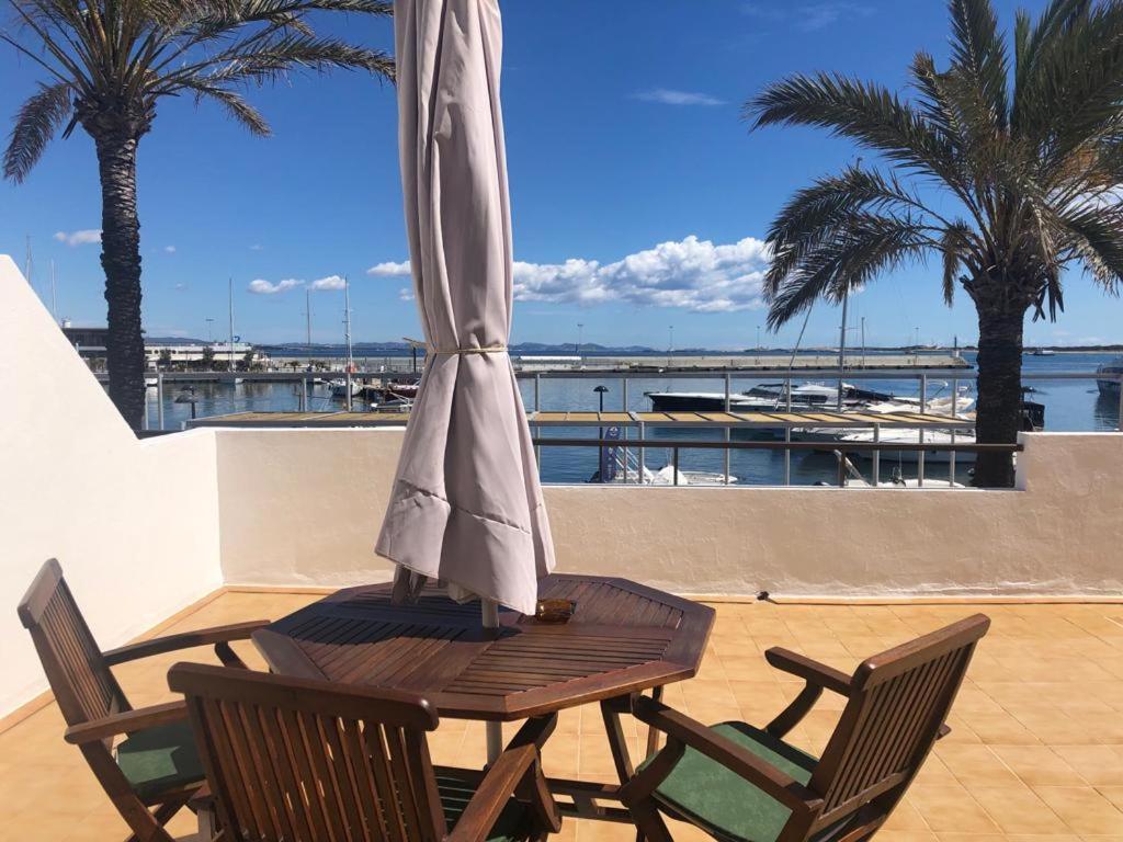 拉萨维纳Apartamentos Mar i Vent Puerto de La Savina Formentera的庭院里配有一张木桌和椅子及遮阳伞