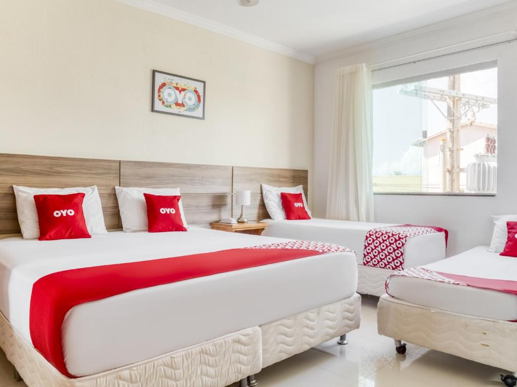 萨尔瓦多OYO Hotel Stella Maris - Salvador的卧室内的两张床,配有红色和白色枕头