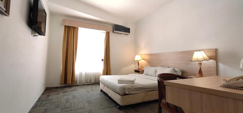 马六甲马六甲普瑞玛酒店的配有一张床、一张书桌和一扇窗户的酒店客房