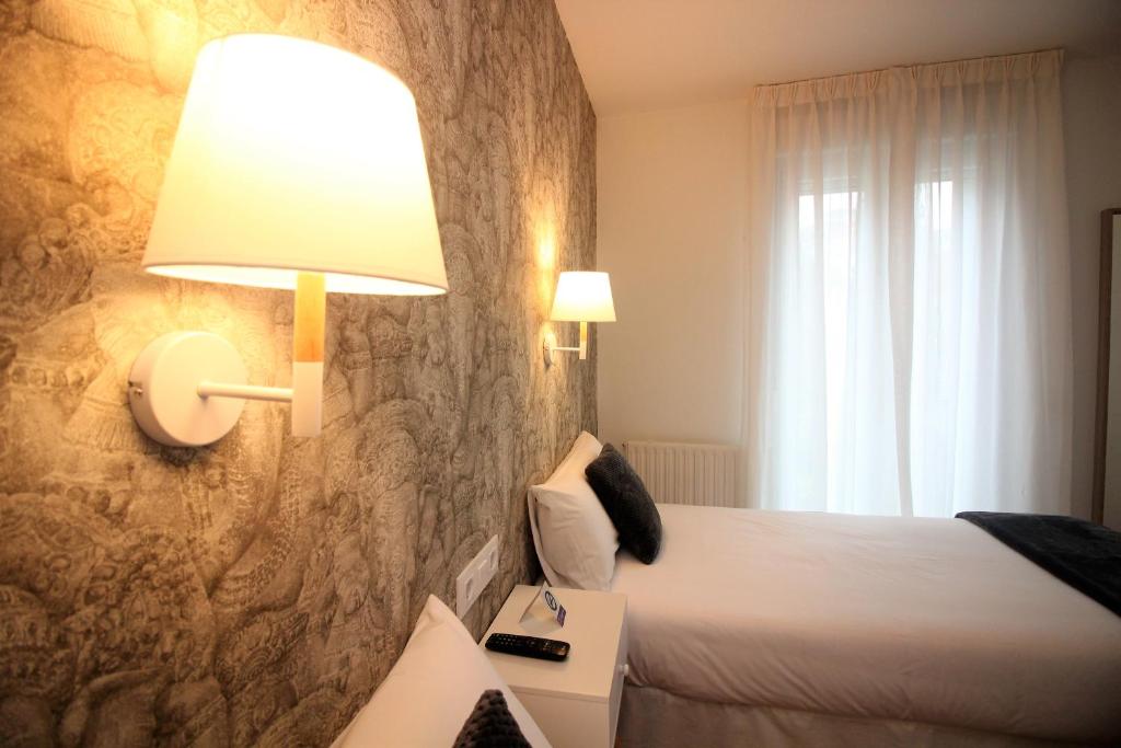 维拉加尔西亚·德·阿劳萨Hotel Vilagarcia的一间卧室配有一张床,墙上配有一盏灯