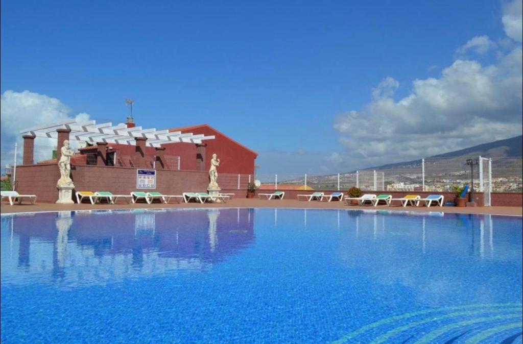 阿德耶villas Canarias的大楼前带椅子的大型游泳池