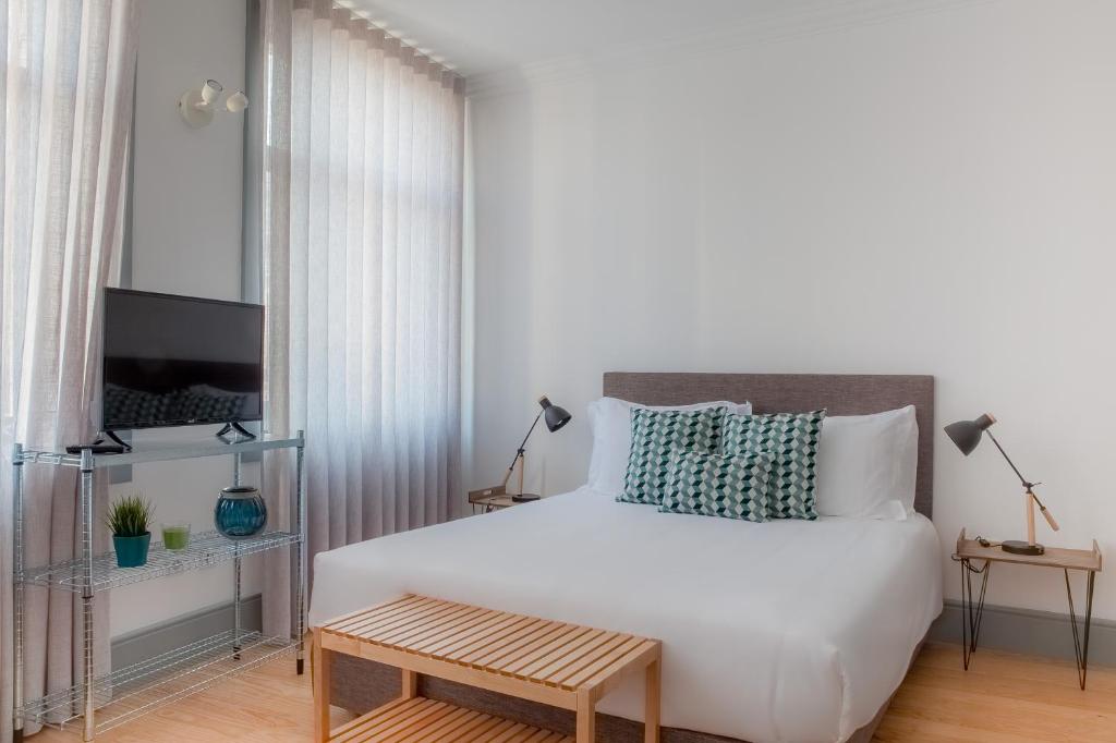 波尔图卡里祖城市休闲公寓的卧室配有一张白色的大床和一张桌子