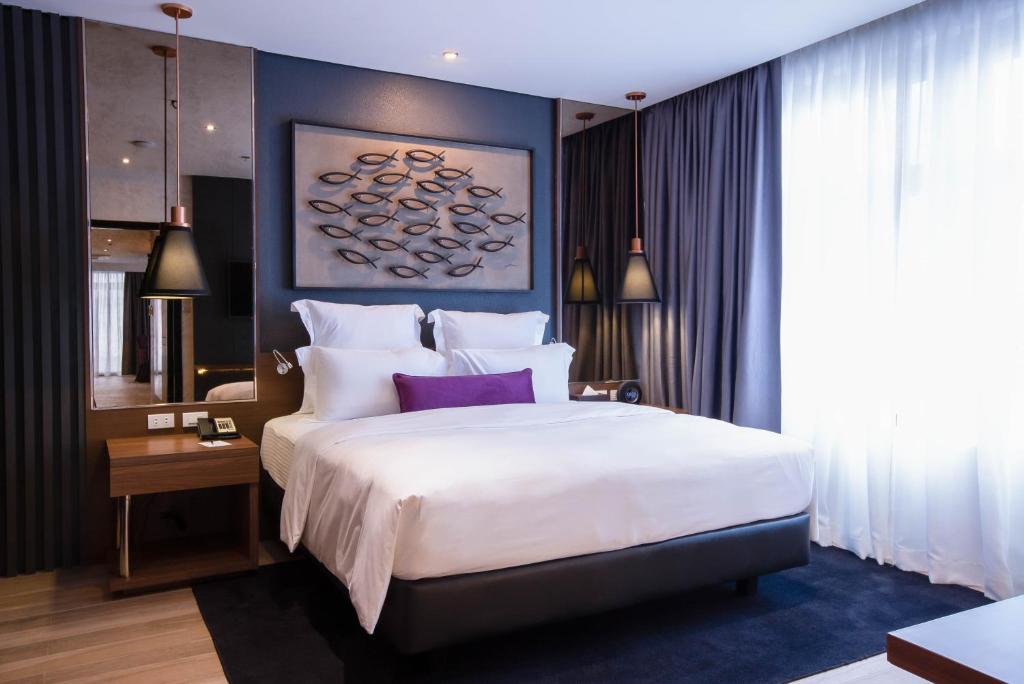 马尼拉Coro Hotel的卧室配有一张带紫色枕头的大型白色床。