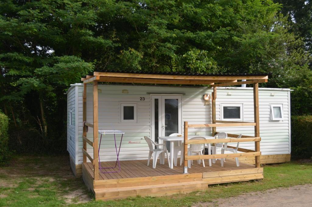 NesmyCamping La Venise Du Bocage的小屋在甲板上配有桌椅