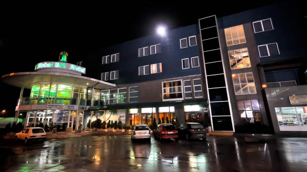 萨拉热窝BM酒店的一座有汽车在晚上停在停车场的建筑