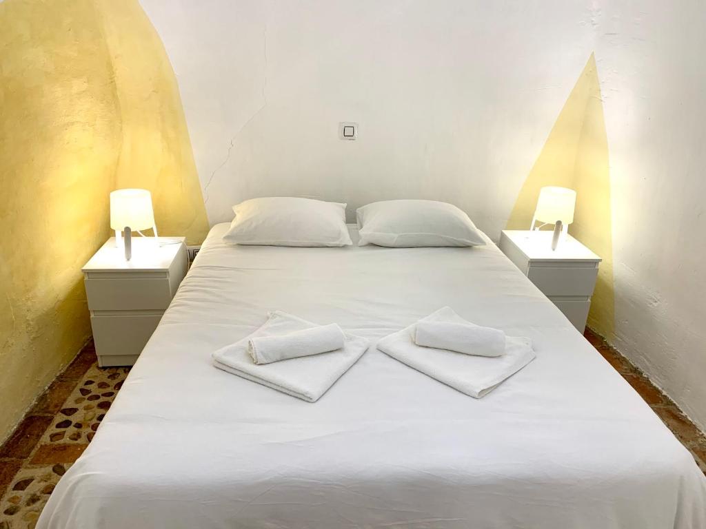 Perales de TajuñaCasa Cueva Castillo的一张白色的床,上面有两条白色毛巾
