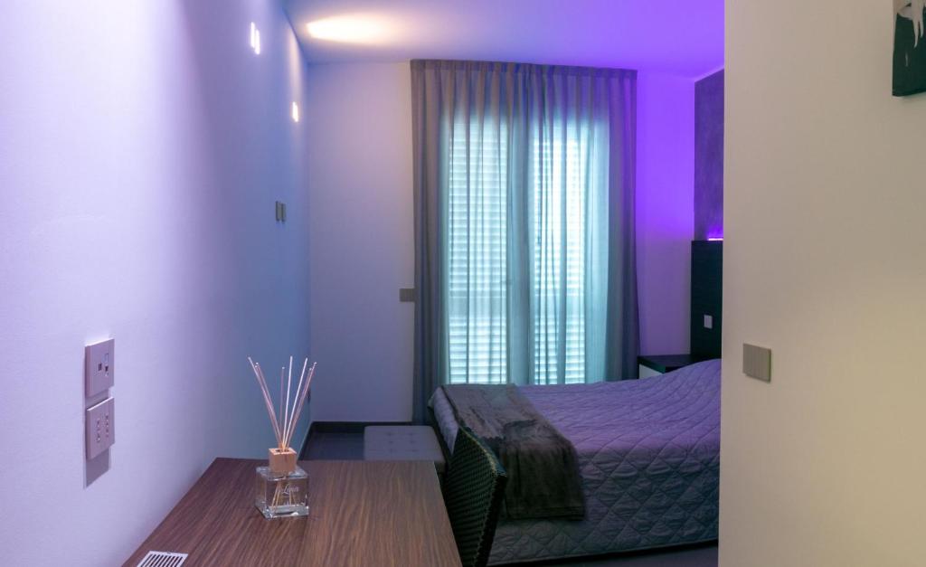 米萨诺阿德里亚蒂科BRIGANTE SUITES的一间紫色照明的卧室和一张带桌子的床