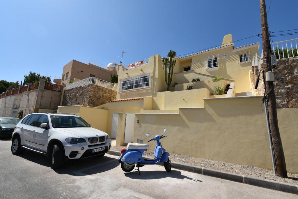 阿桂拉斯Villa Bonita en Aguilas Murcia con piscina privada的停在房子前面的汽车和摩托车